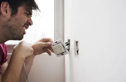 Instalação de tomadas e interruptores com fios expostos em parede residencial.