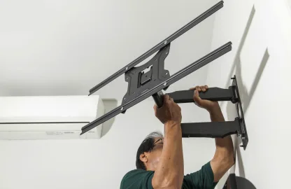 Marido de aluguel instalando suporte articulado para TV na parede.