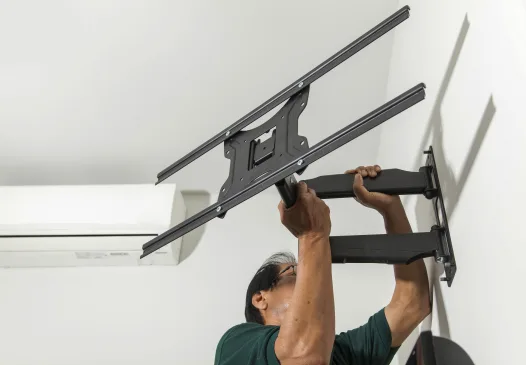Marido de aluguel instalando suporte articulado para TV na parede.