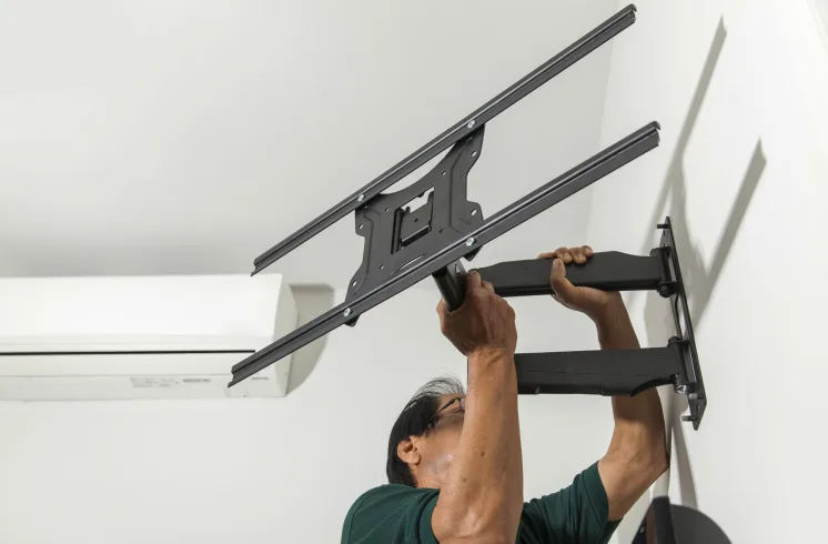 Marido de aluguel instalando suporte articulado para TV na parede.