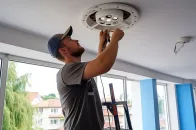 Pequenos reparos domésticos: profissional conserta luminária no teto de um ambiente interno.