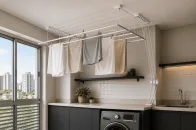 Lavanderia moderna com varal de teto instalado próximo à janela, aproveitando a ventilação natural para secagem eficiente das roupas.